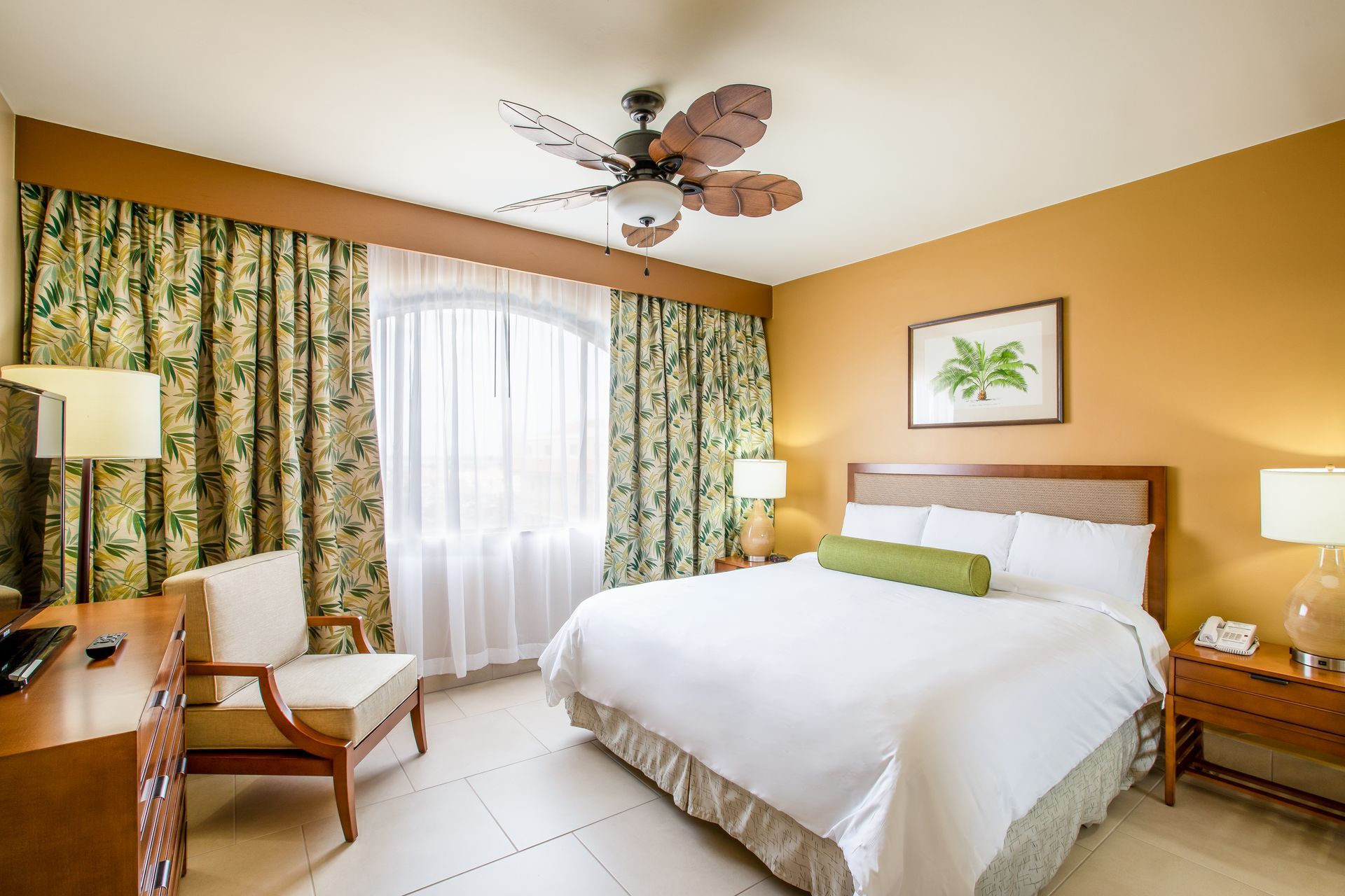A hotel room with a king size bed and a ceiling fan.
