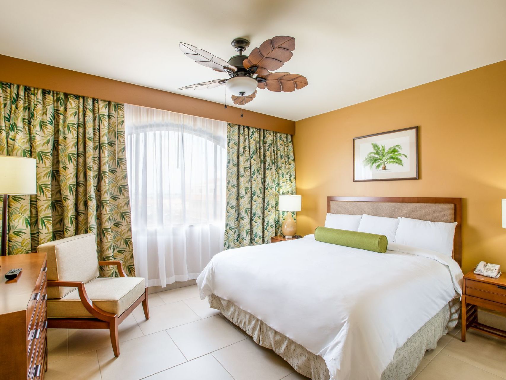 A hotel room with a king size bed and a ceiling fan.