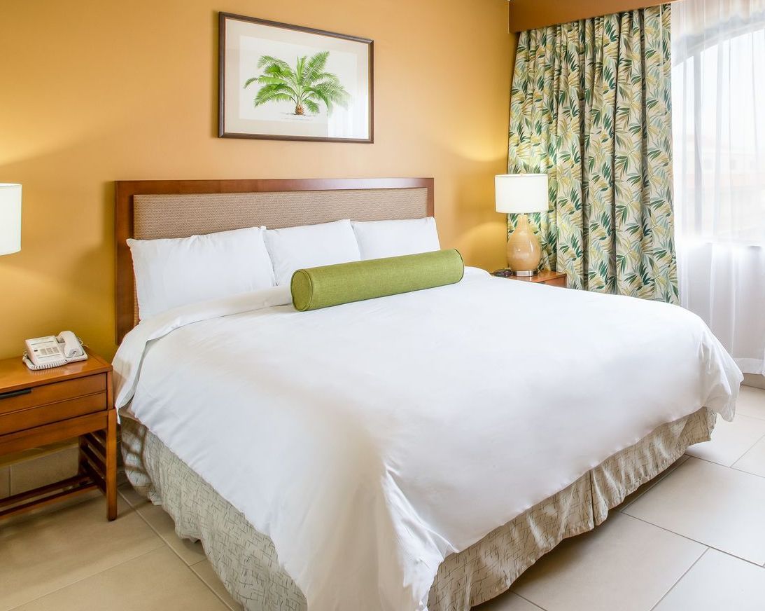 A hotel room with a large bed and a picture on the wall above it