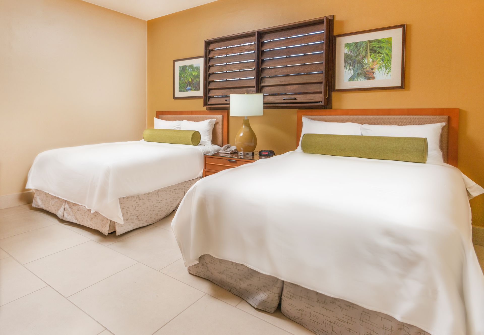 A hotel room with a king size bed , chairs , lamps and a bench.