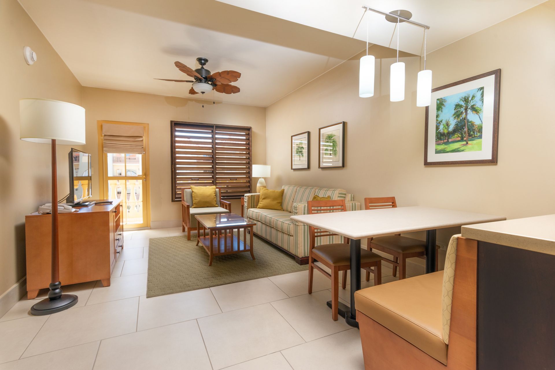 A living room with a couch , table , chairs and a ceiling fan.