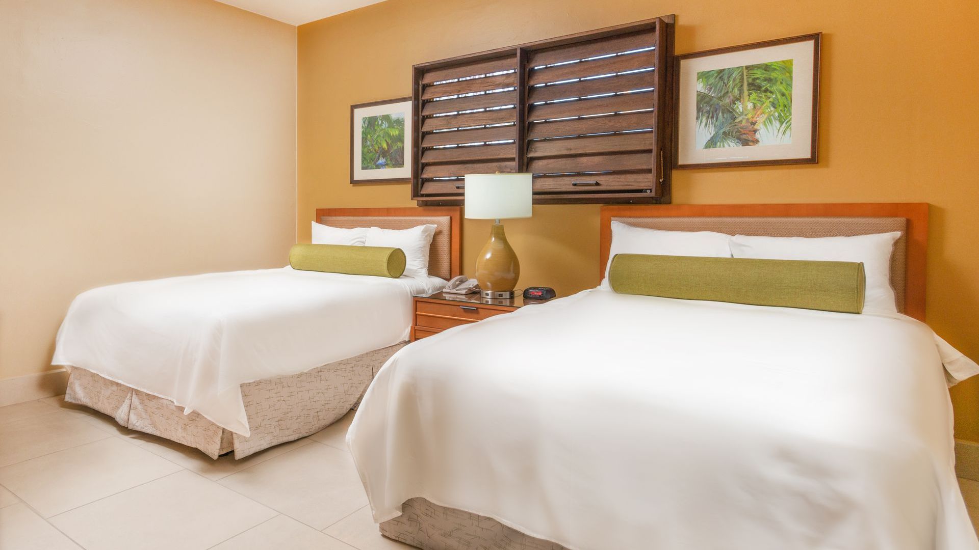 A hotel room with two beds and a lamp.