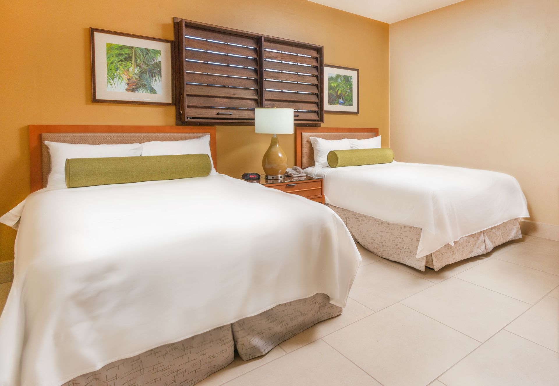 A hotel room with a king size bed , chairs , lamps and a bench.