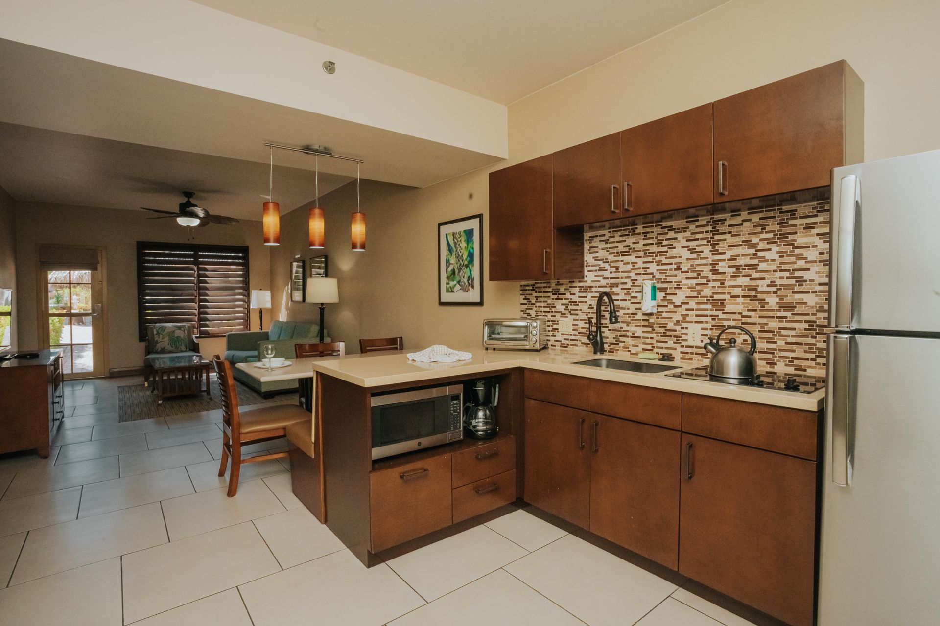 A kitchen with stainless steel appliances and wooden cabinets in a hotel room.