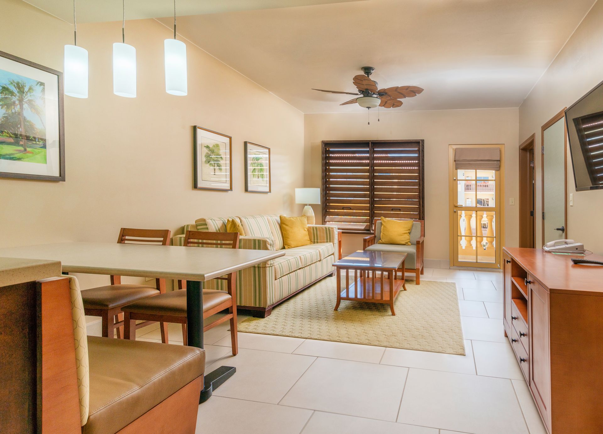 A living room with a couch , table , chairs and a ceiling fan