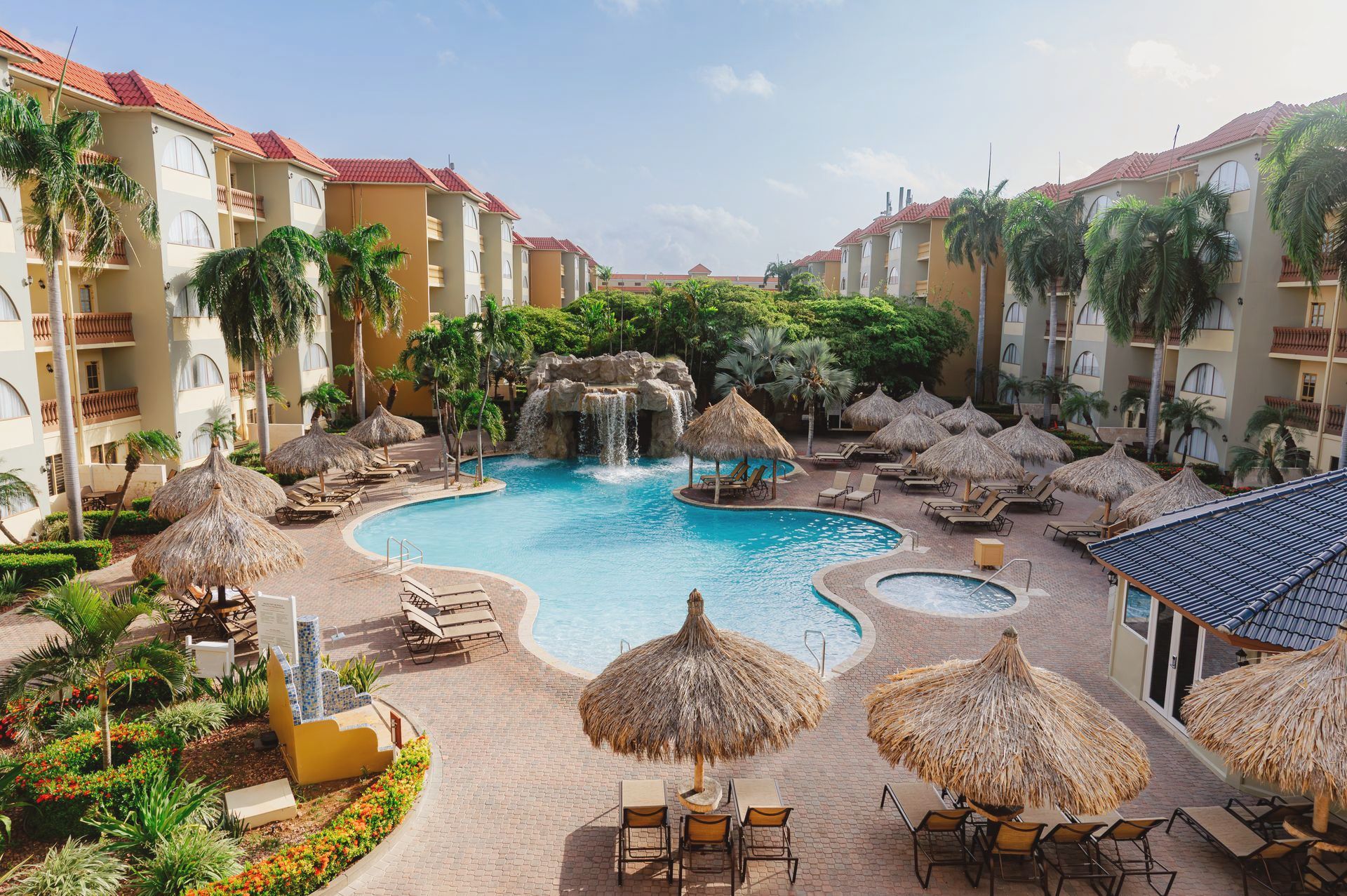 An aerial view of a large swimming pool surrounded by chairs and umbrellas.