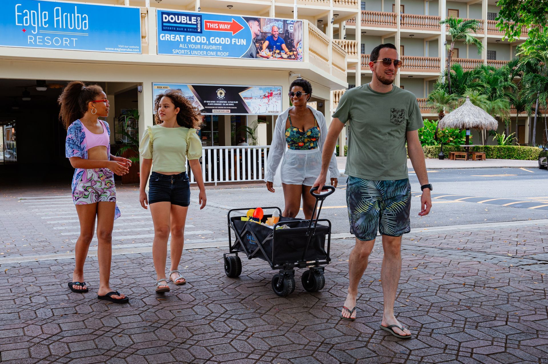 A group of people are walking down a sidewalk with a wagon.