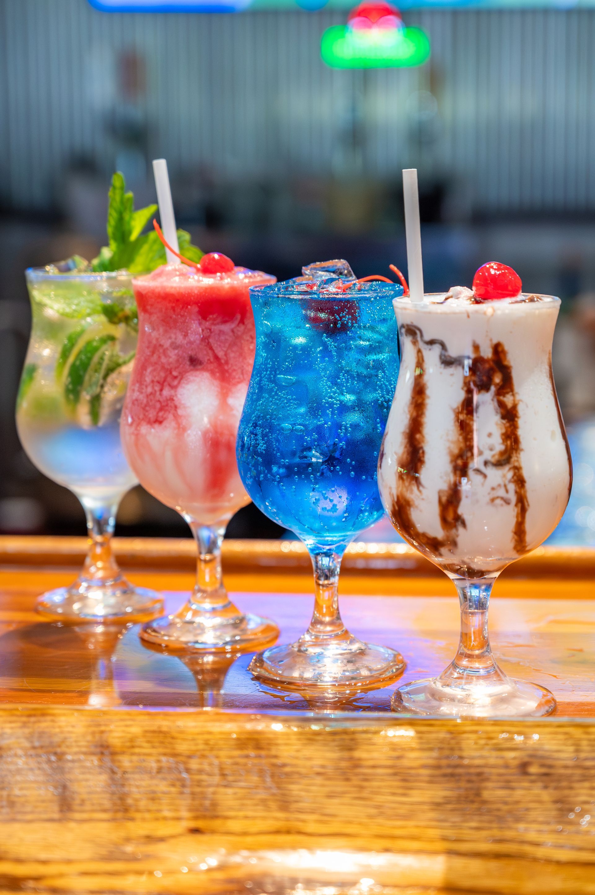 Three different types of cocktails are sitting on a wooden bar.