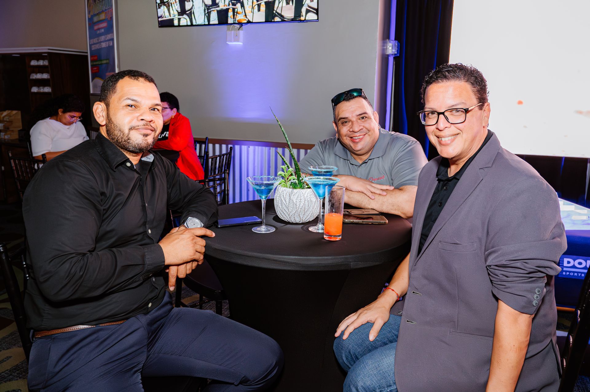 Three men are sitting at a table with drinks in a restaurant.