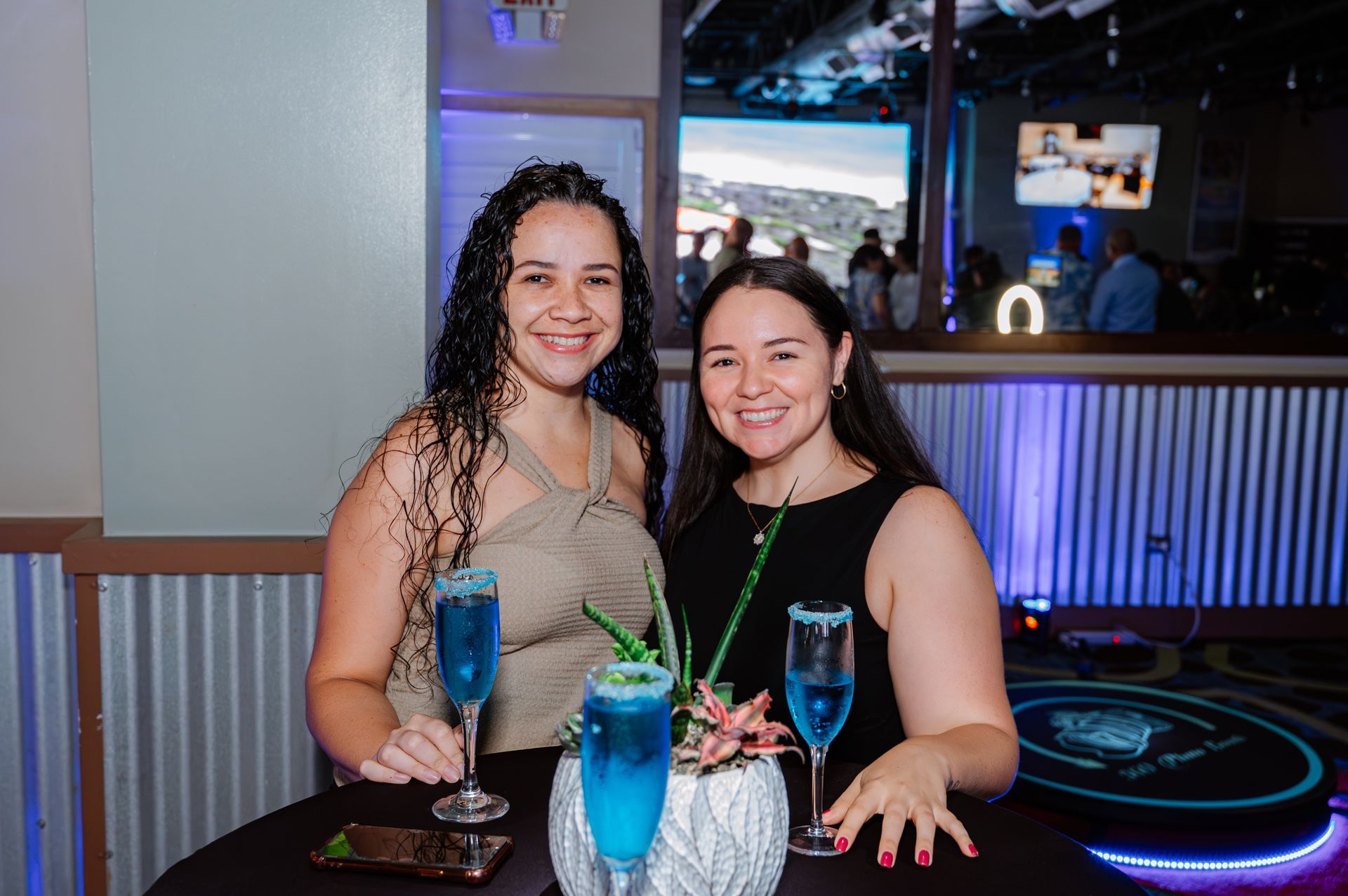 Two women are sitting at a table with drinks.