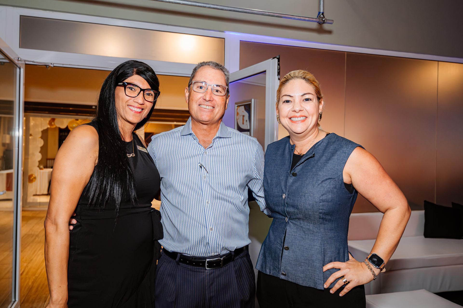 A man and two women are posing for a picture in a living room.