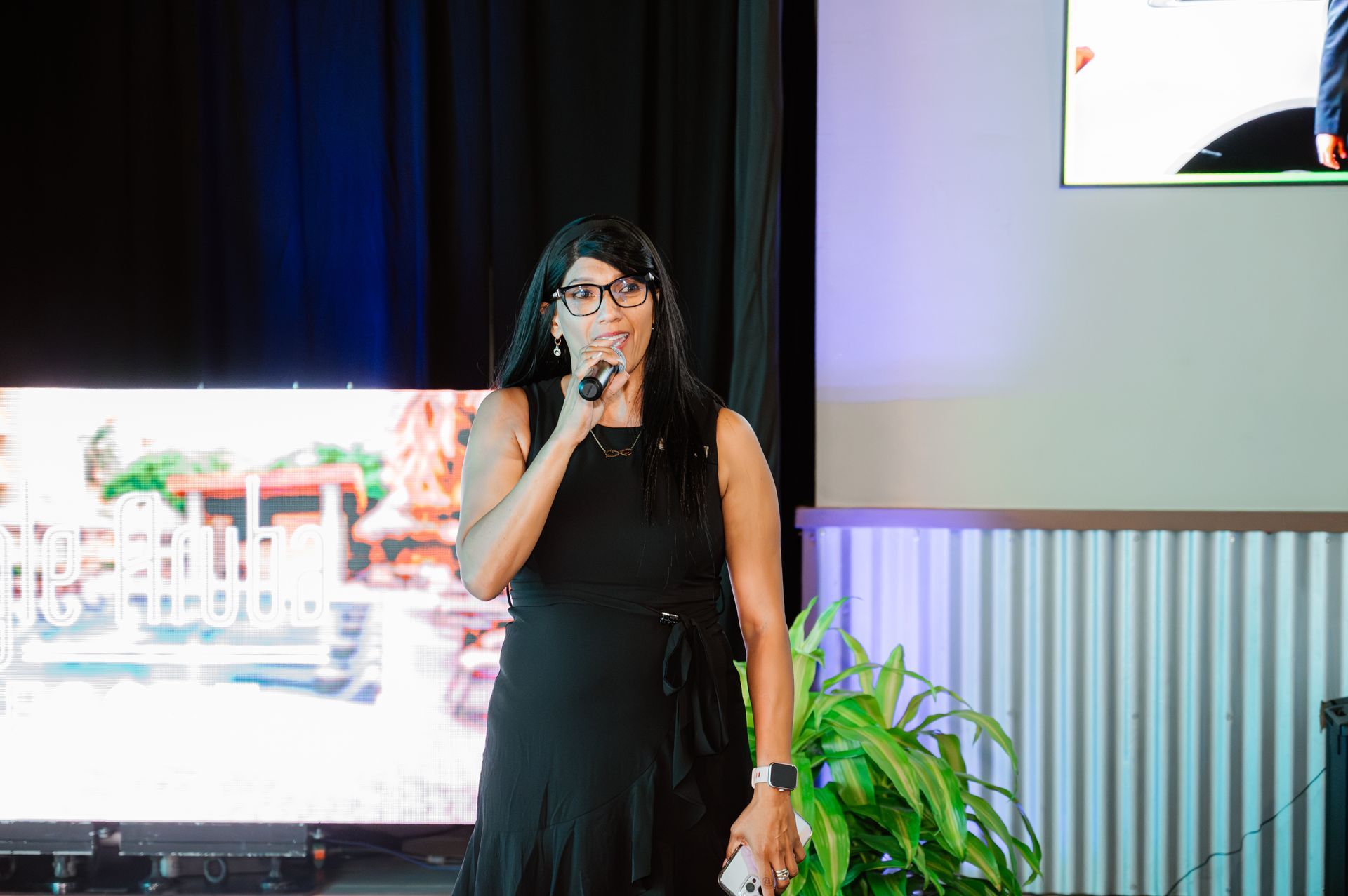 A woman in a black dress is standing in front of a microphone.