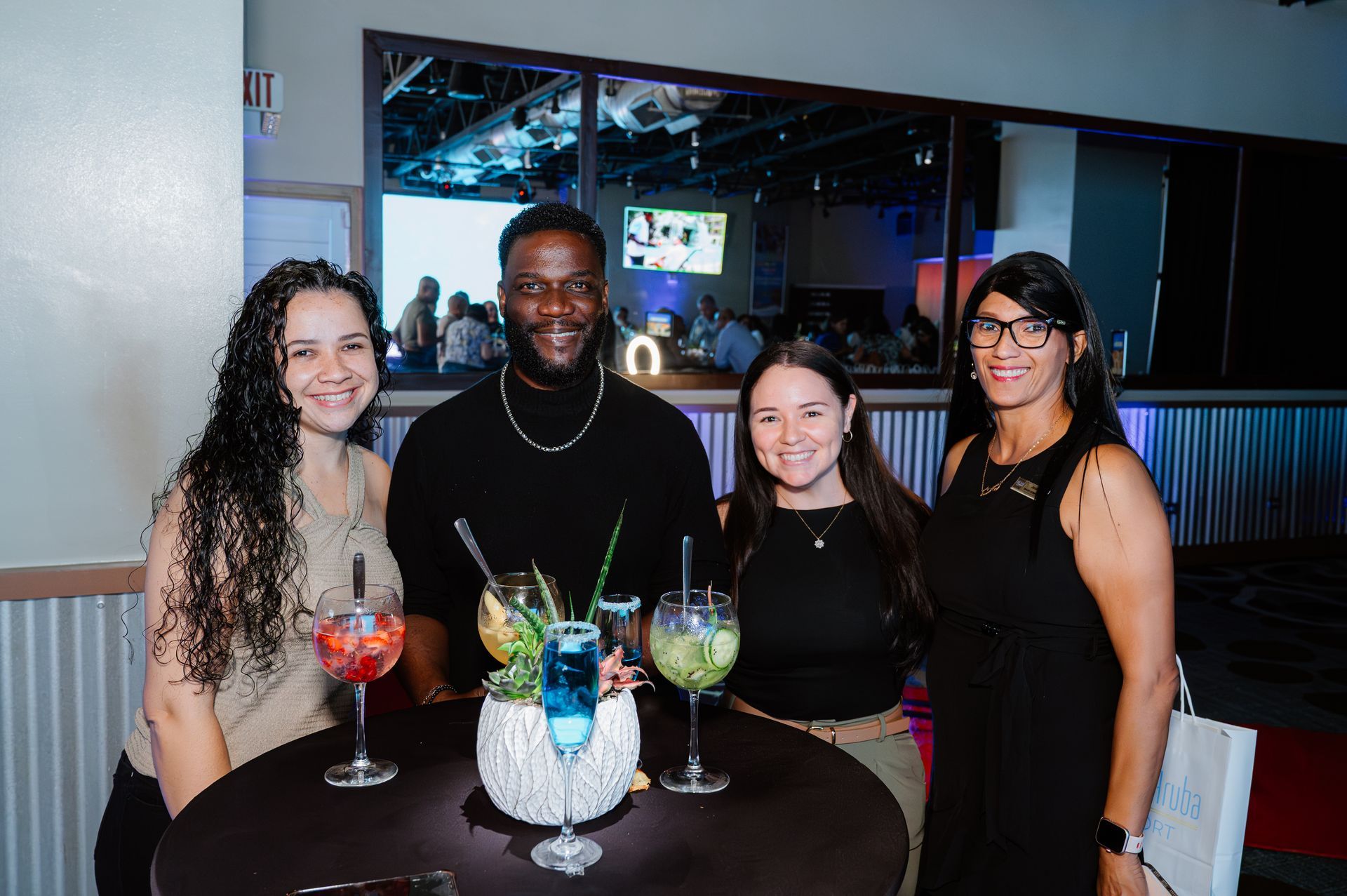 A group of people are posing for a picture at a table with drinks.
