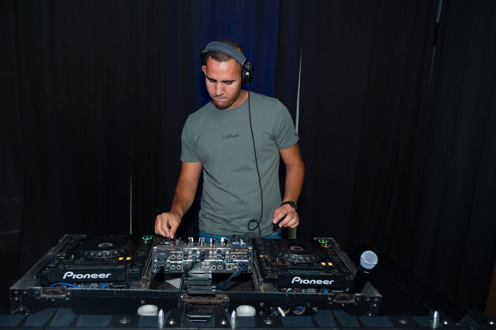 A man wearing headphones is playing music on a dj set.