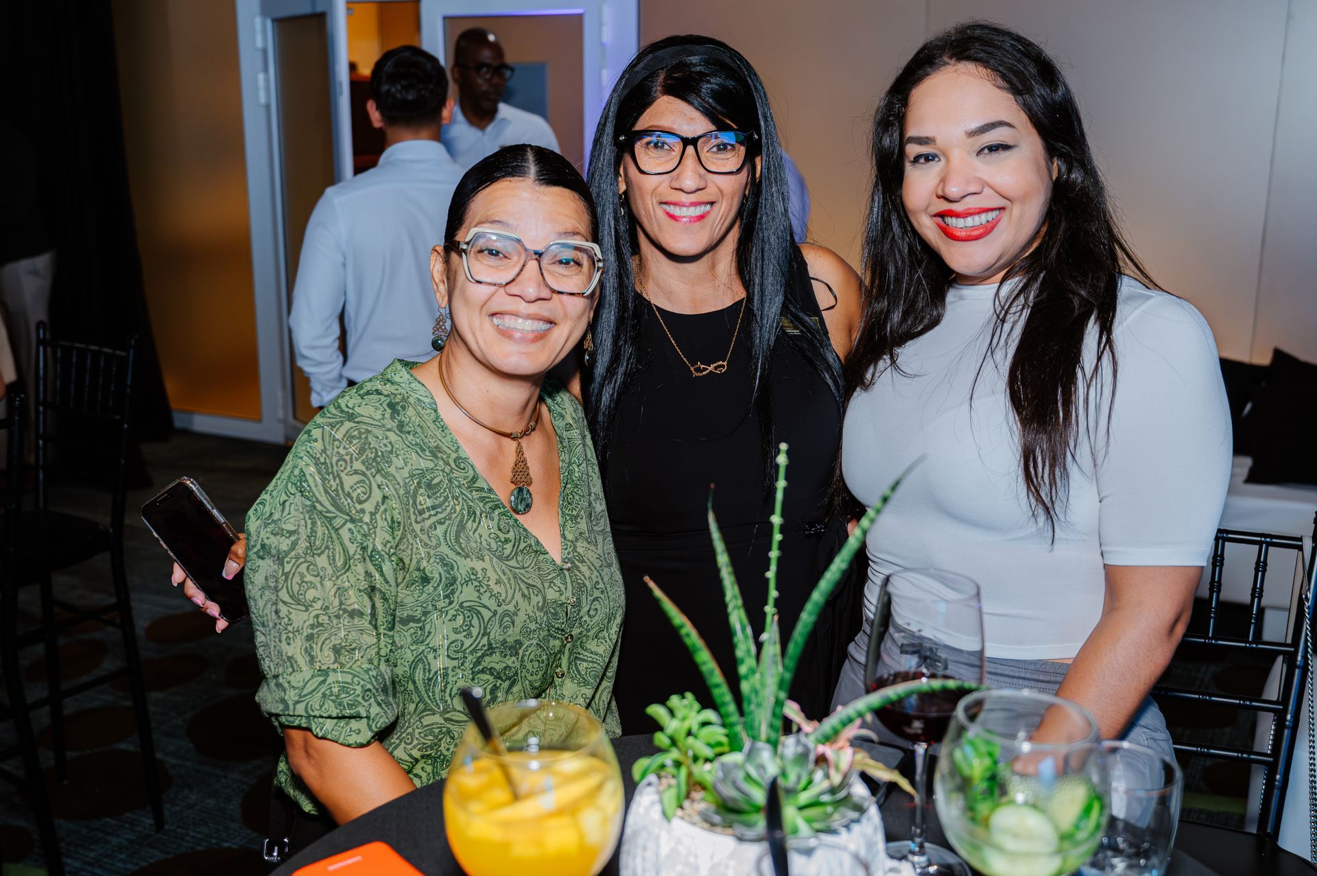 Three women are posing for a picture at a party.