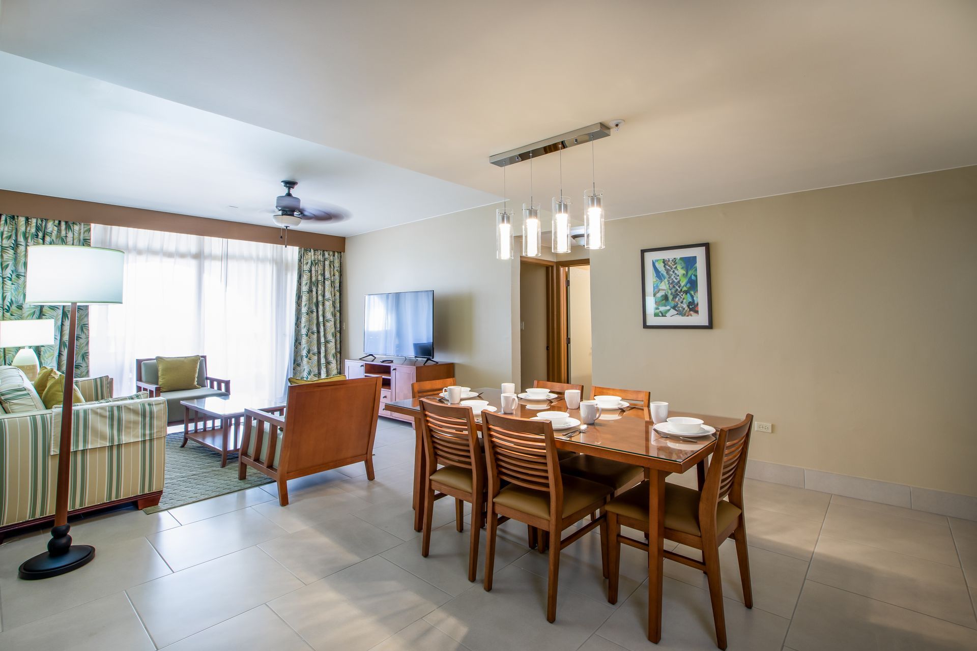 A living room with a dining table and chairs and a ceiling fan.