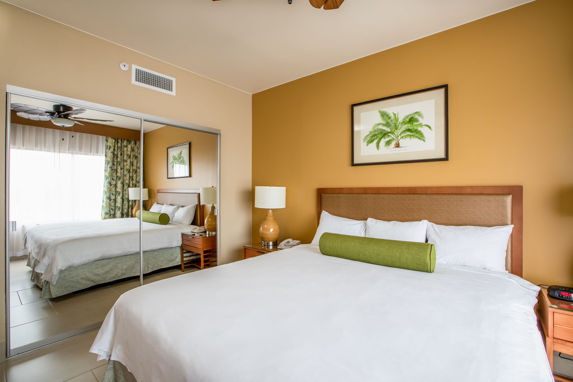 A hotel room with a king size bed and a large mirror.