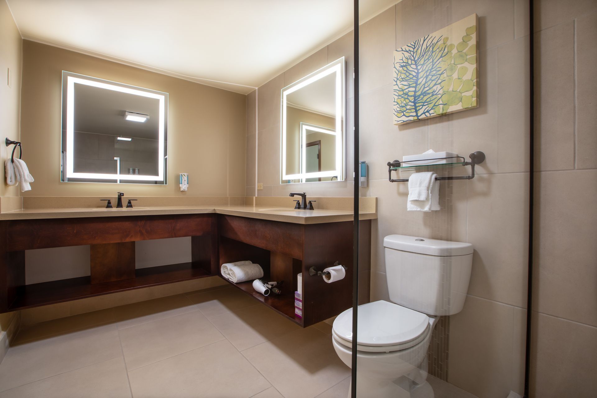 A bathroom in a hotel room with a toilet , sink and mirror.