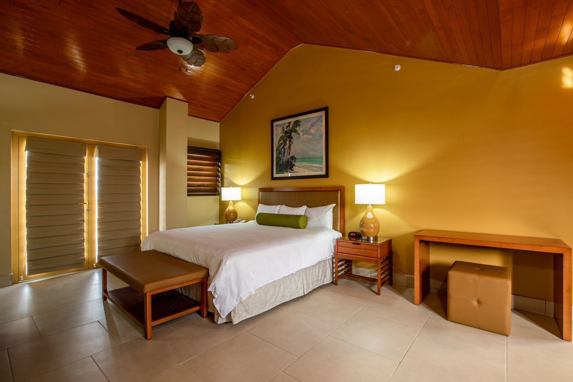 A hotel room with a king size bed and a ceiling fan.