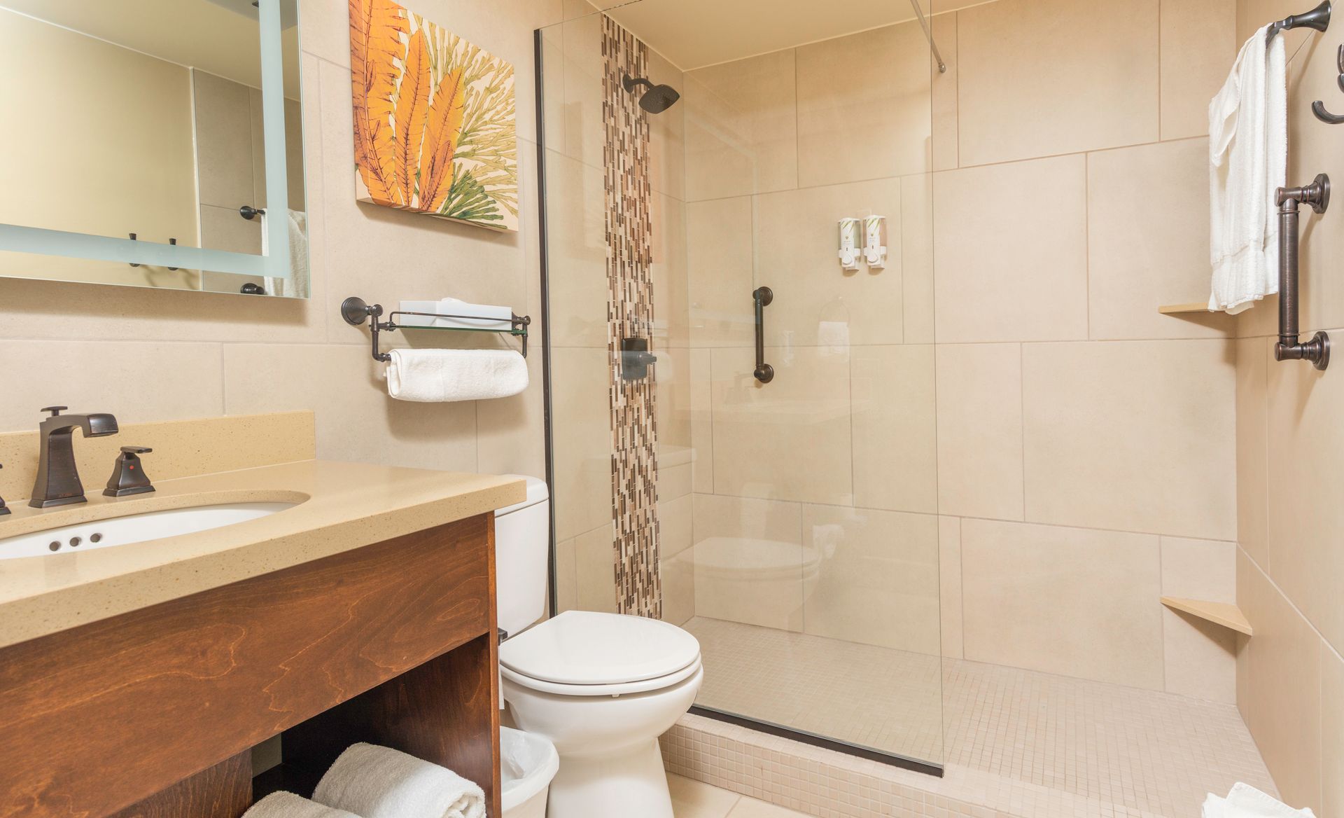 A bathroom with a toilet , sink , mirror and walk in shower.