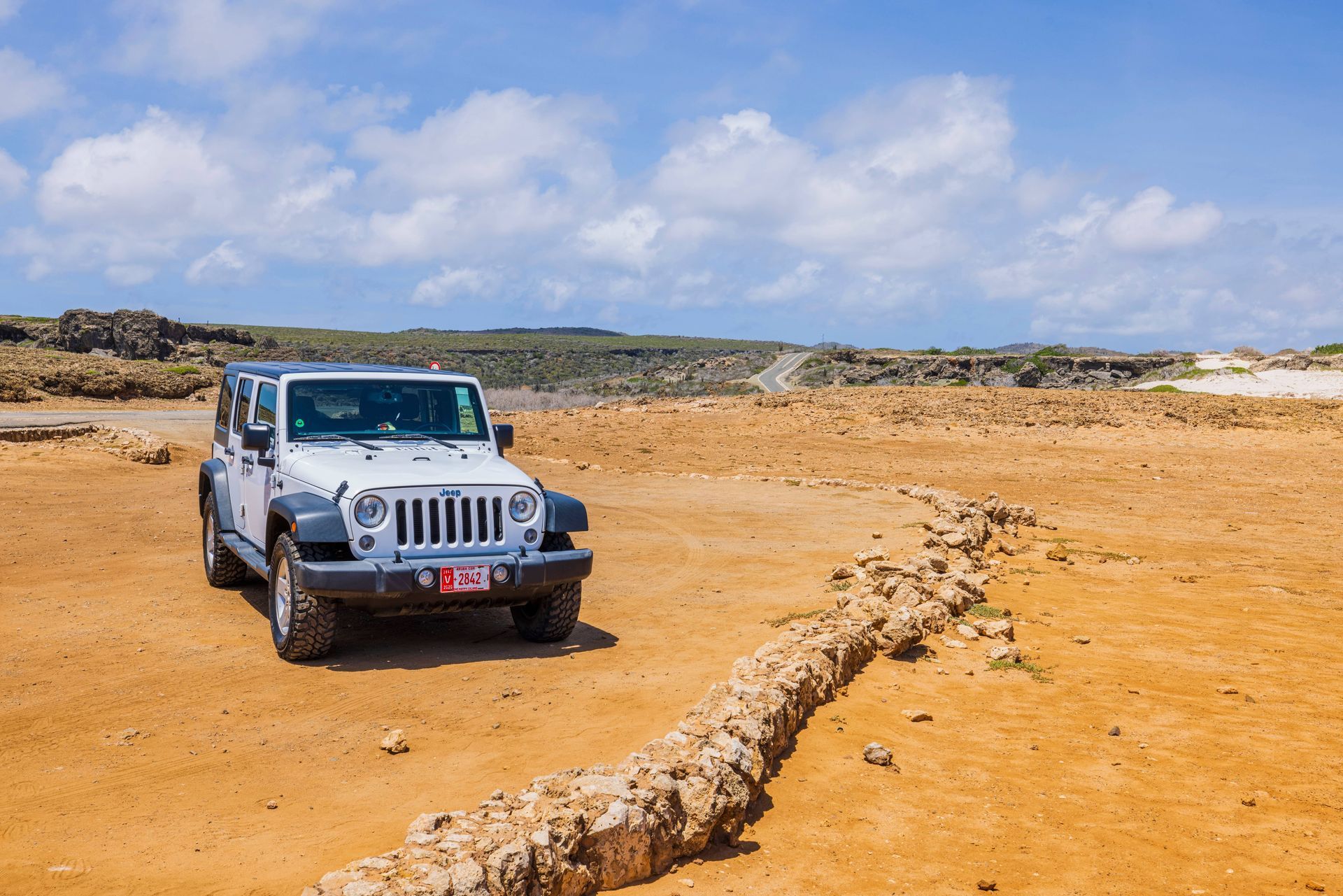 Scenic coastal road in Aruba with clear blue skies and ocean views.