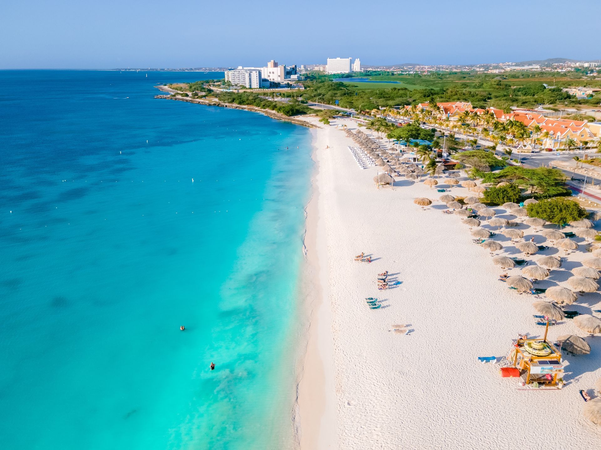 An aerial view of a beach with white sand and turquoise water.