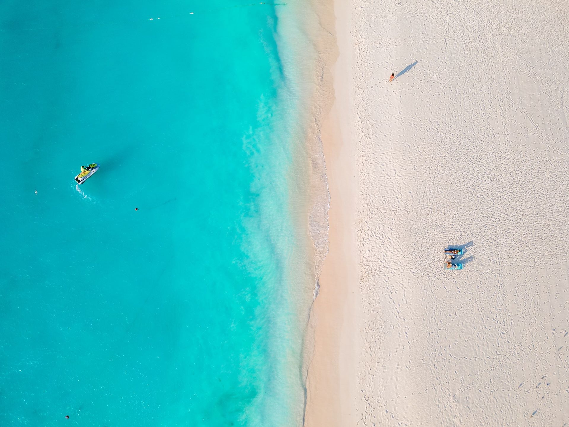 An aerial view of a beach with people swimming in the ocean.