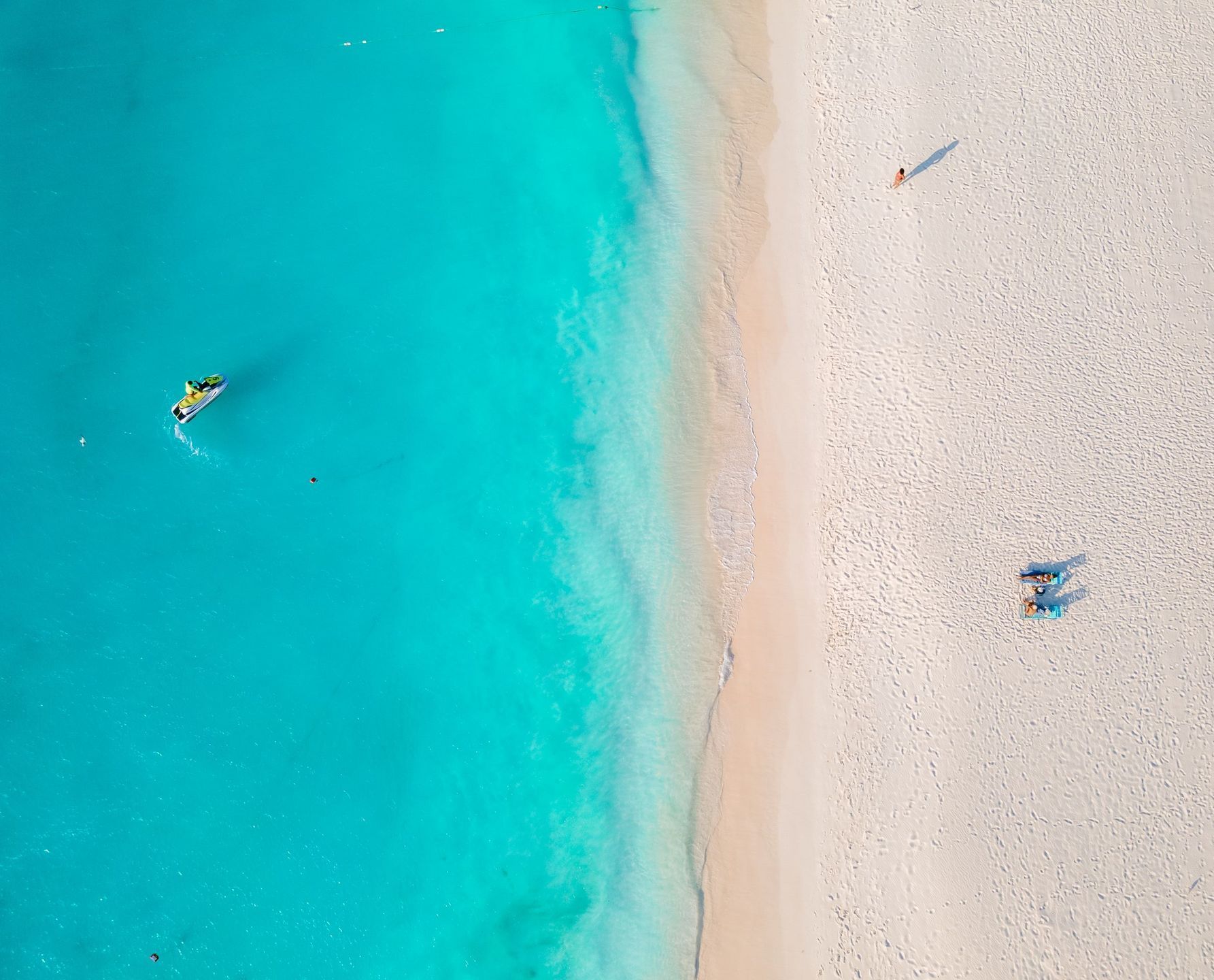 An aerial view of a beach with white sand and turquoise water.