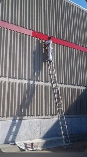 A man on a ladder paints the side of a building