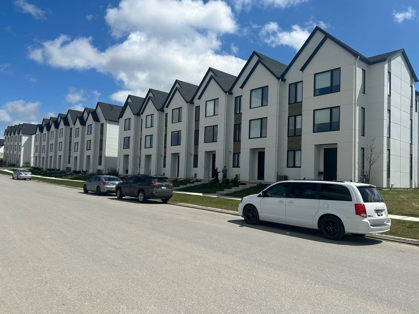 A white van is parked in front of a row of apartment buildings.