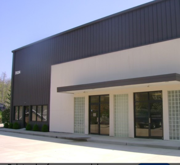A white building with a brown roof and a few windows