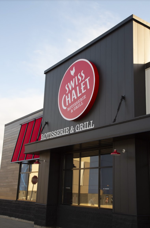 The front of a swiss chalet restaurant with a red sign