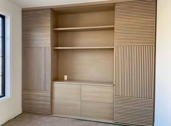 A room with a lot of shelves and drawers and a window.