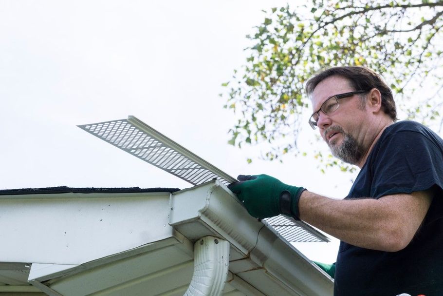 Technicians using vacuum and brush tools for gutter cleaning.