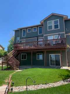 A large house with a large deck and stairs in the backyard.