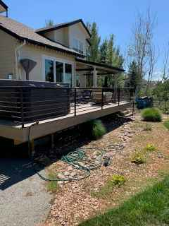 A large house with a large deck and a hot tub on it.