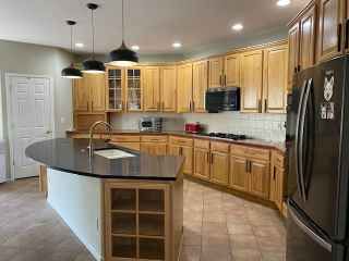 A kitchen with wooden cabinets , granite counter tops , and a black refrigerator.