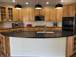 A kitchen with wooden cabinets and a black granite counter top.