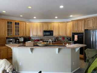 A kitchen with wooden cabinets , stainless steel appliances , and a large island.