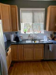A kitchen with wooden cabinets , stainless steel appliances , a sink , and a window.