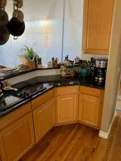 A kitchen with wooden cabinets , granite counter tops , a stove and a coffee maker.