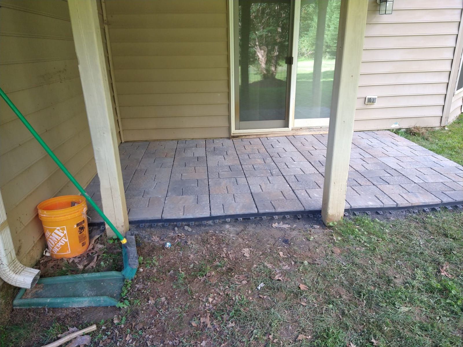 A patio with a broom and bucket next to a house.