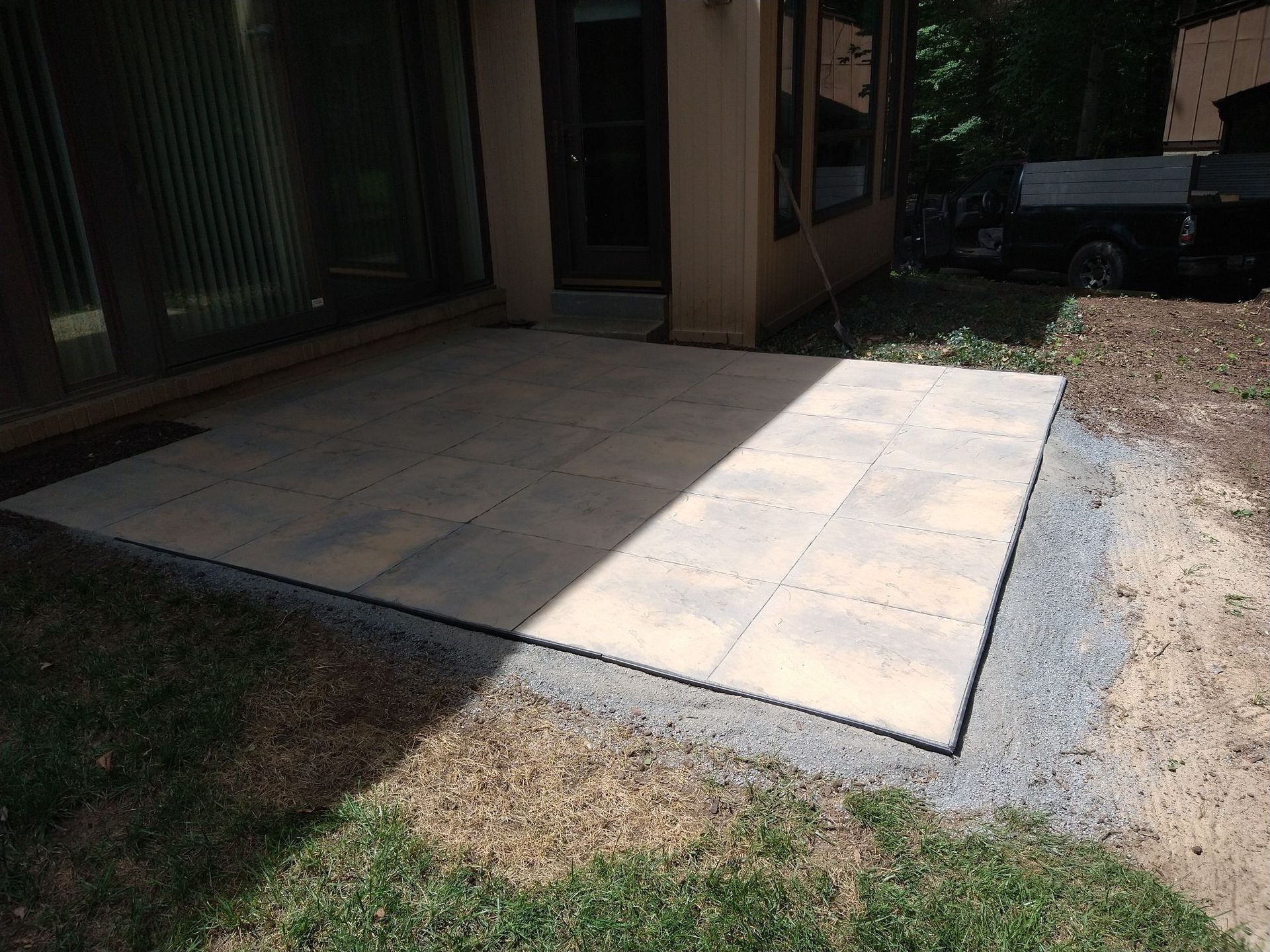 A patio is being built in the backyard of a house.