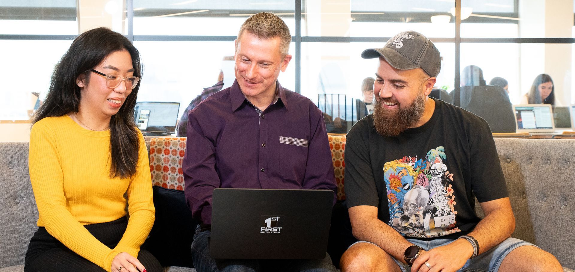 Three people are sitting on a couch looking at a laptop, learning about local SEO tactics to improve small business visibility online