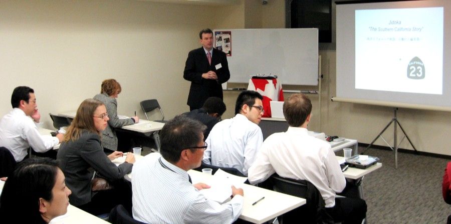 Ron Haigh gives a presentation to a class of people seated at desks in a room.