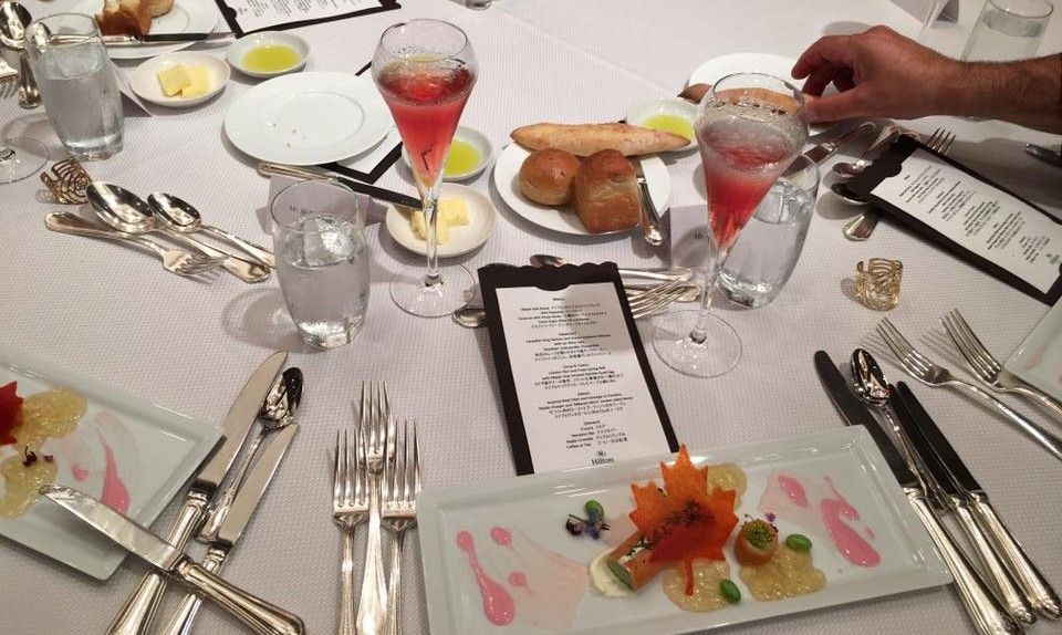 Group of people posing with a Canadian flag in front of a traditional Japanese building.