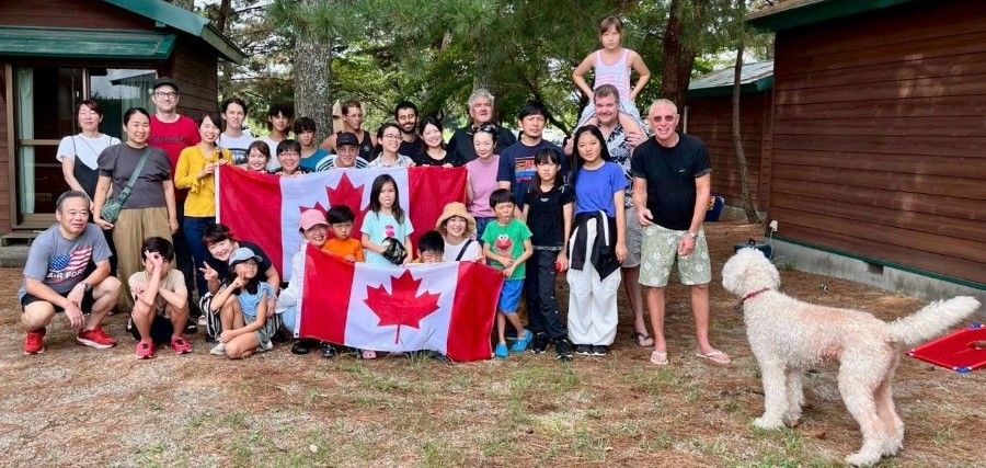 Group of people holding a Canadian flag outdoors, with a dog.