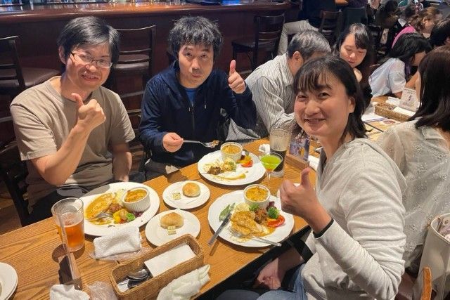 People at a table in a restaurant give thumbs up. Turkey dinner plates and drinks are visible.