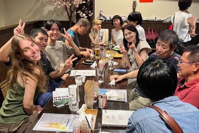 Group of people smiling and making peace signs at a restaurant table.