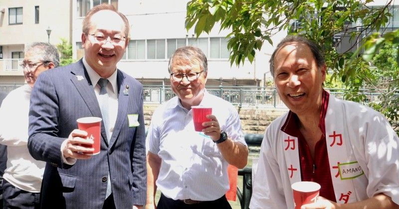 Three people outdoors smiling and holding red cups at a casual gathering